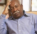 An older African-American man sits with a worried expression