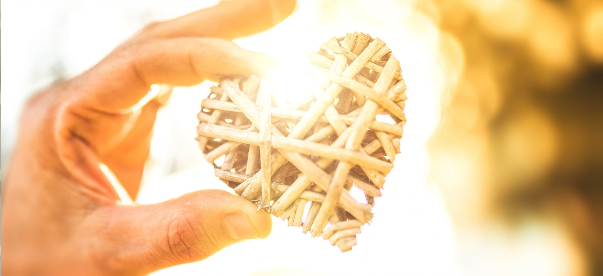 A hand holds a wooden woven heart